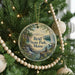 A round ornament on a Christmas tree, featuring a scenic landscape with a waterfall and mountains, with the text "Reid State Park, Maine" displayed on it.