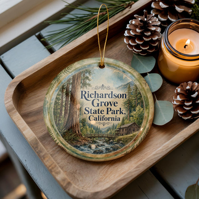 A wooden tray with a decorative ornament featuring a scenic image of a forest and a small cabin, accompanied by pine cones and a lit candle.