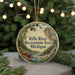 A round ornament with a scenic image of a river, pine trees, and a waterfall, along with the text "Rifle River Recreation Area, Michigan".