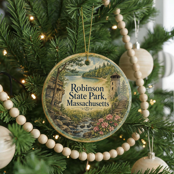 A round ornament hanging on a Christmas tree, featuring a scenic landscape with a castle, trees, and a river.