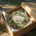 A decorative ornament in a box, featuring a scenic image of Rock Island Trail State Park in Illinois.