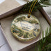 A decorative ornament in a box, featuring a scenic image of Roland Cooper State Park in Alabama.