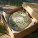 A decorative ornament in a box, featuring a scenic image of Rosaryville State Park, Maryland.