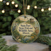 A round ornament with a nature scene and text, hanging on a string.