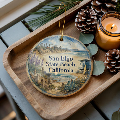 A decorative ornament with a beach scene and the text "San Elijo State Beach, California" is displayed on a wooden tray, accompanied by pine cones and a lit candle.