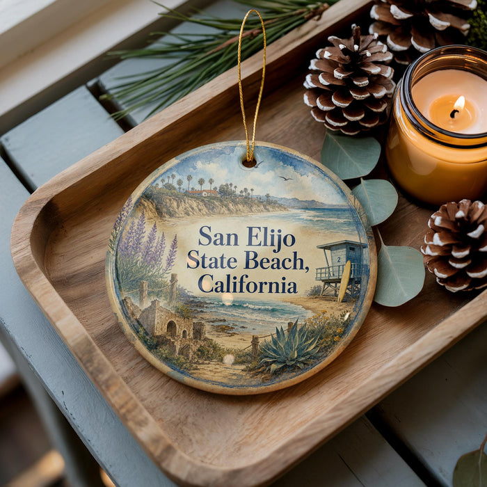 A decorative ornament with a beach scene and the text "San Elijo State Beach, California" is displayed on a wooden tray, accompanied by pine cones and a lit candle.