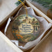 A decorative ornament in a white box, featuring a painting of a historical landmark and a bell tower.