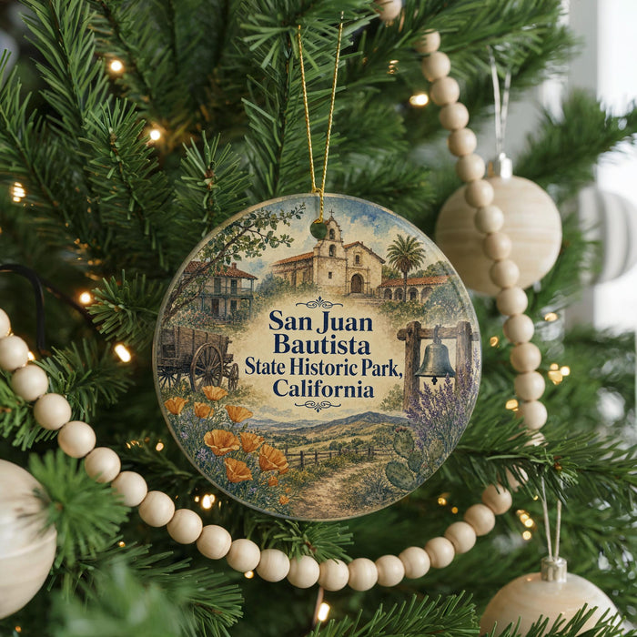 A round ornament hanging on a Christmas tree, featuring a scenic illustration of San Juan Bautista State Historic Park, California.