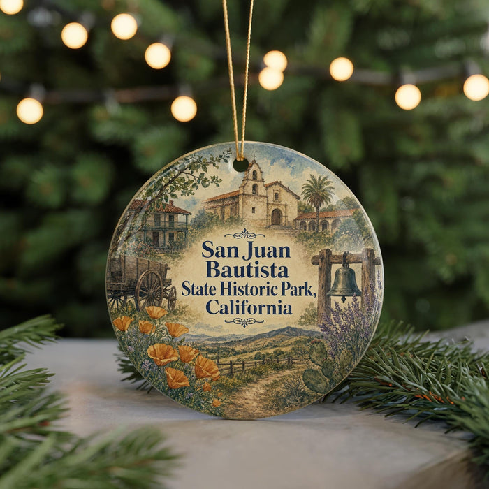 A round ornament with a painting of Santa Juan Bautista State Historic Park, California, featuring a bell tower, a church, and a field with flowers.