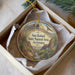 A decorative ornament in a box, featuring a scenic landscape with mountains, cacti, and a bird in flight.