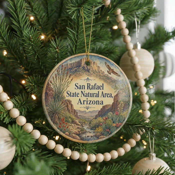 A round ornament hanging on a Christmas tree, featuring a desert landscape with mountains and cacti.