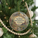 A round ornament hanging on a Christmas tree, featuring a desert landscape with mountains and cacti.