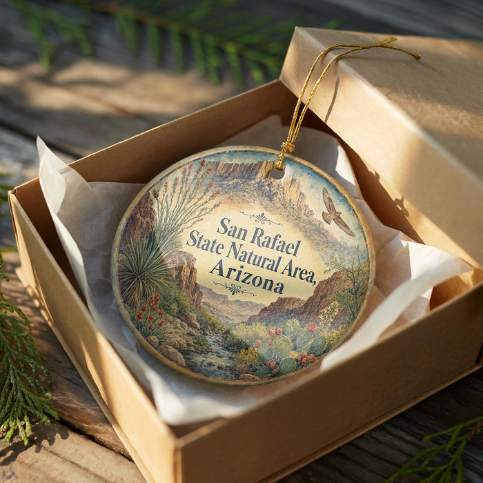 A decorative ornament in a cardboard box, featuring a scenic landscape with mountains, desert plants, and a bird in flight.