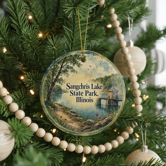 A round ornament hanging on a Christmas tree, featuring a scenic image of a lake and a small building.