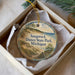 A decorative ornament in a box, featuring a scenic image of a beach and dunes with the text "Saugatuck Dunes State Park, Michigan".