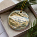 A decorative ornament in a box, featuring a scenic image of Saugatuck Dunes State Park, Michigan.