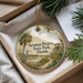 A decorative ornament with a bird and palm trees, placed in a box with pine branches.