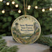 A round ornament with a scenic mountain landscape and a tower, hanging on a string.