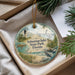 A decorative ornament with a lighthouse and a bird, placed in a box with pine branches.