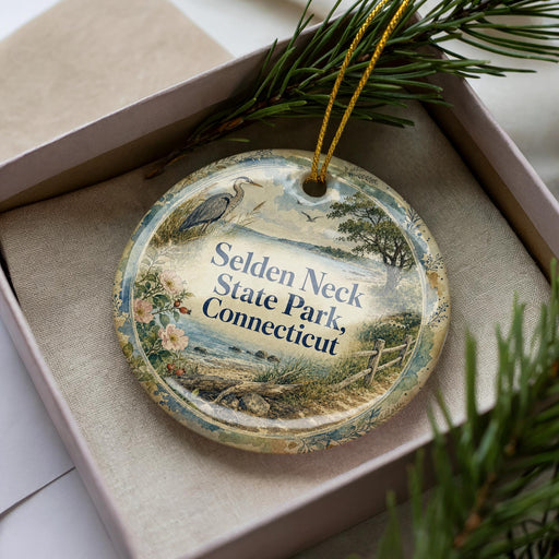 A decorative ornament in a box, featuring a scenic landscape with a bird and trees, along with the text "SELDEN NECK STATE PARK, CONNECTICUT".