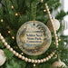 A round ornament hanging on a Christmas tree, featuring a scenic image of a park and a bird.
