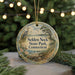 A round ornament with a scenic image of a bird and a landscape, hanging from a string.