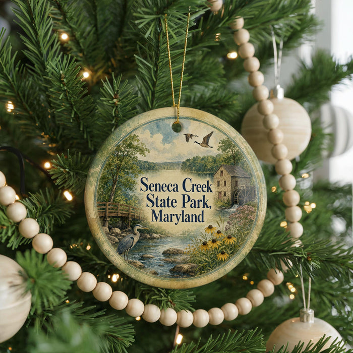 A round ornament hanging on a Christmas tree, featuring a scenic image of Seneca Creek State Park, Maryland.