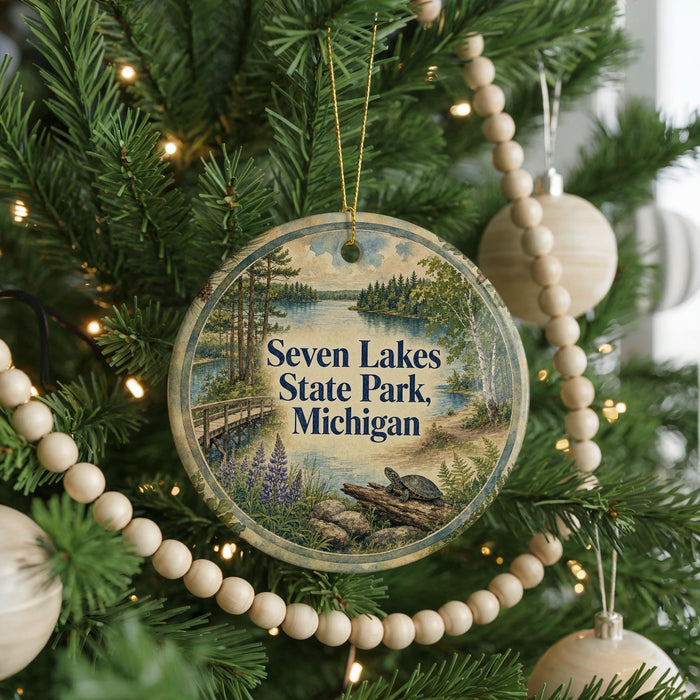 A circular ornament hanging on a Christmas tree, featuring a scenic image of Seven Lakes State Park in Michigan.