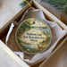 A decorative ornament in a box, featuring a scenic landscape with a lake, trees, and wildlife.