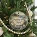 A round ornament hanging on a Christmas tree, featuring a scenic image of Shackford Head State Park, Maine.