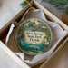 A decorative ornament in a box, featuring a scenic image of Silver Springs State Park in Florida, with a manatee and palm trees in the background.
