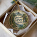 A decorative ornament in a box, featuring a scenic landscape with a waterfall and forest.