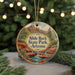 A circular ornament featuring a scenic landscape with a waterfall and mountains, hanging from a string.