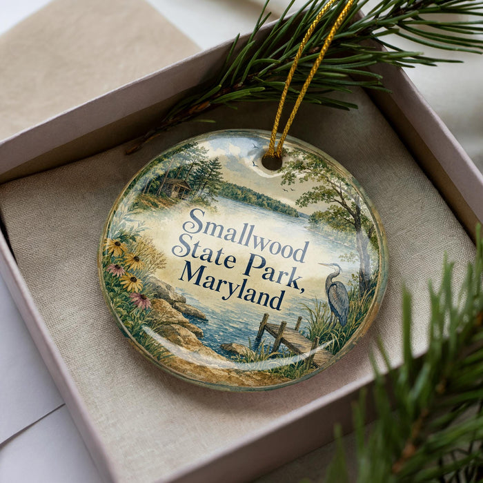 A decorative ornament in a box, featuring a scenic landscape with a lake, trees, and a bird, along with the text "Smallwood State Park, Maryland".