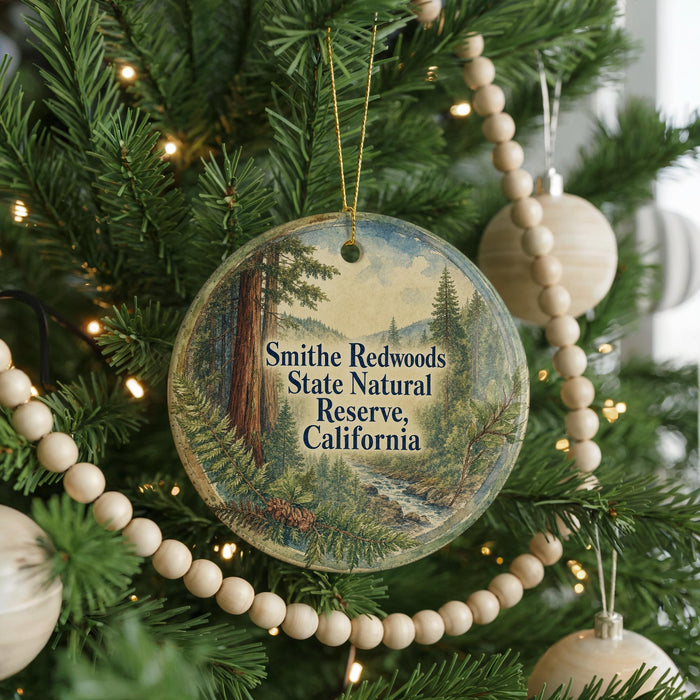 A round ornament hanging on a Christmas tree, featuring a scenic image of the Smithe Redwoods State Natural Reserve in California.