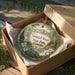 A decorative ornament in a wooden box, featuring a scenic landscape with a deer and flowers, with the text "Smithall Woods State Park, Georgia" printed on it.