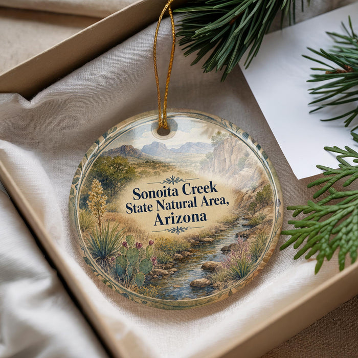 A decorative ornament with a scenic landscape of Sonoita Creek, the Sonoita Creek State Natural Area in Arizona, displayed in a box with pine branches.