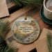 A decorative ornament with a scenic landscape of Sonoteca Creek, the Sonoteca Creek State Natural Area in Arizona, is displayed on a wooden surface alongside a cup of coffee and some pine branches.