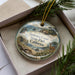 A decorative ornament in a box, featuring a scenic landscape with a lighthouse and a deer, along with the text "Sonoma Coast State Park, California".