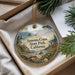A decorative ornament with a lighthouse and a deer in a forest setting, placed in a box with pine branches.