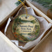 A round ornament with a scenic landscape of Squantz Pond, State Park, Connecticut, hanging from a string.