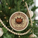 A Christmas tree decorated with ornaments, including a round ornament with a spider image and the text "SPINNY ORB-WEAVER SPIDER".
