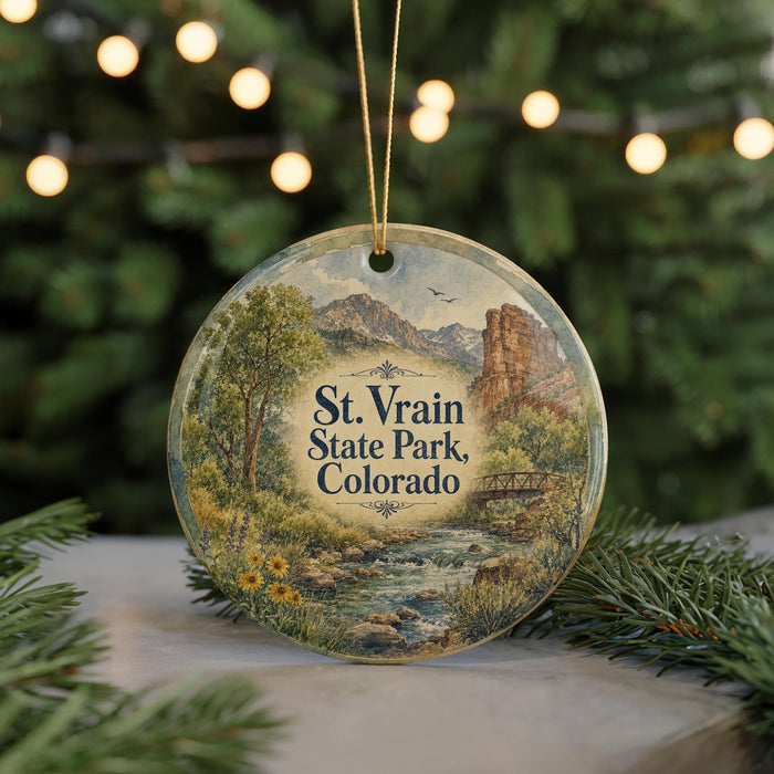 A circular ornament with a scenic landscape of St. Vrain State Park, Colorado, featuring a river, mountains, and greenery.