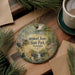 A decorative ornament featuring a scenic image of State Park in Georgia, with a deer and a waterfall, is displayed on a wooden surface alongside a cup of coffee and some pine branches.