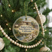 A round ornament hanging on a Christmas tree, featuring a painting of a historic fort and the text "Sutter's Fort State Historic Park, California".