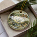A decorative ornament featuring a bird and a scenic landscape, with the text "Sweetwater Creek State Park, Georgia" printed on it.