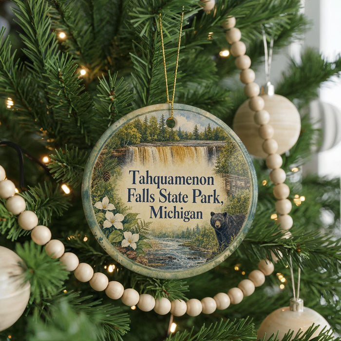 A circular ornament hanging on a Christmas tree, featuring a scenic image of Taquamenon Falls State Park in Michigan.