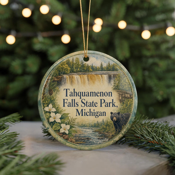 A round ornament with a painting of Tahquamenon Falls State Park, Michigan, featuring a black bear and a waterfall.