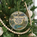A round ornament hanging on a Christmas tree, featuring an illustration of a coastal scene with palm trees and a body of water.