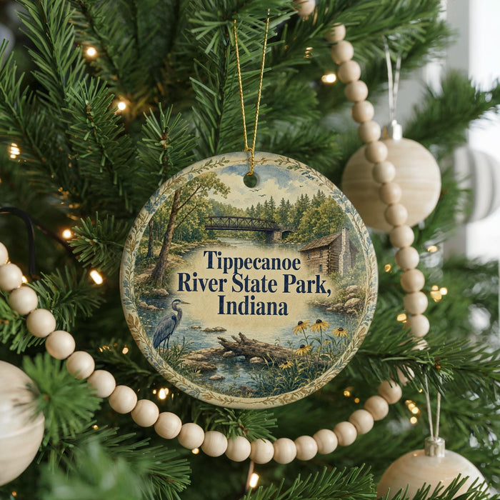 A round ornament hanging on a Christmas tree, featuring a scenic image of Tippecanoe River State Park, Indiana.